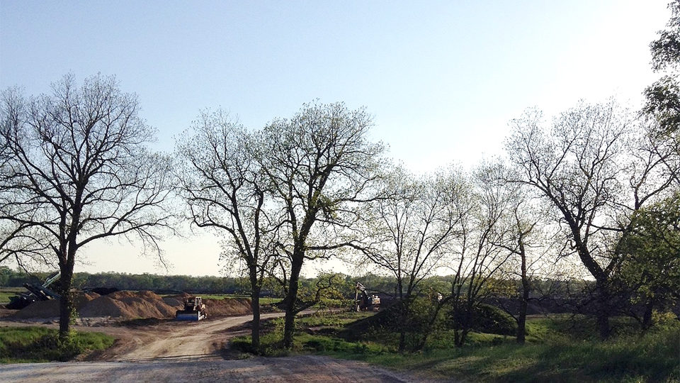 A dirt road with trees and a sky background