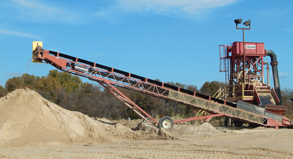 A large conveyor belt is in the dirt.