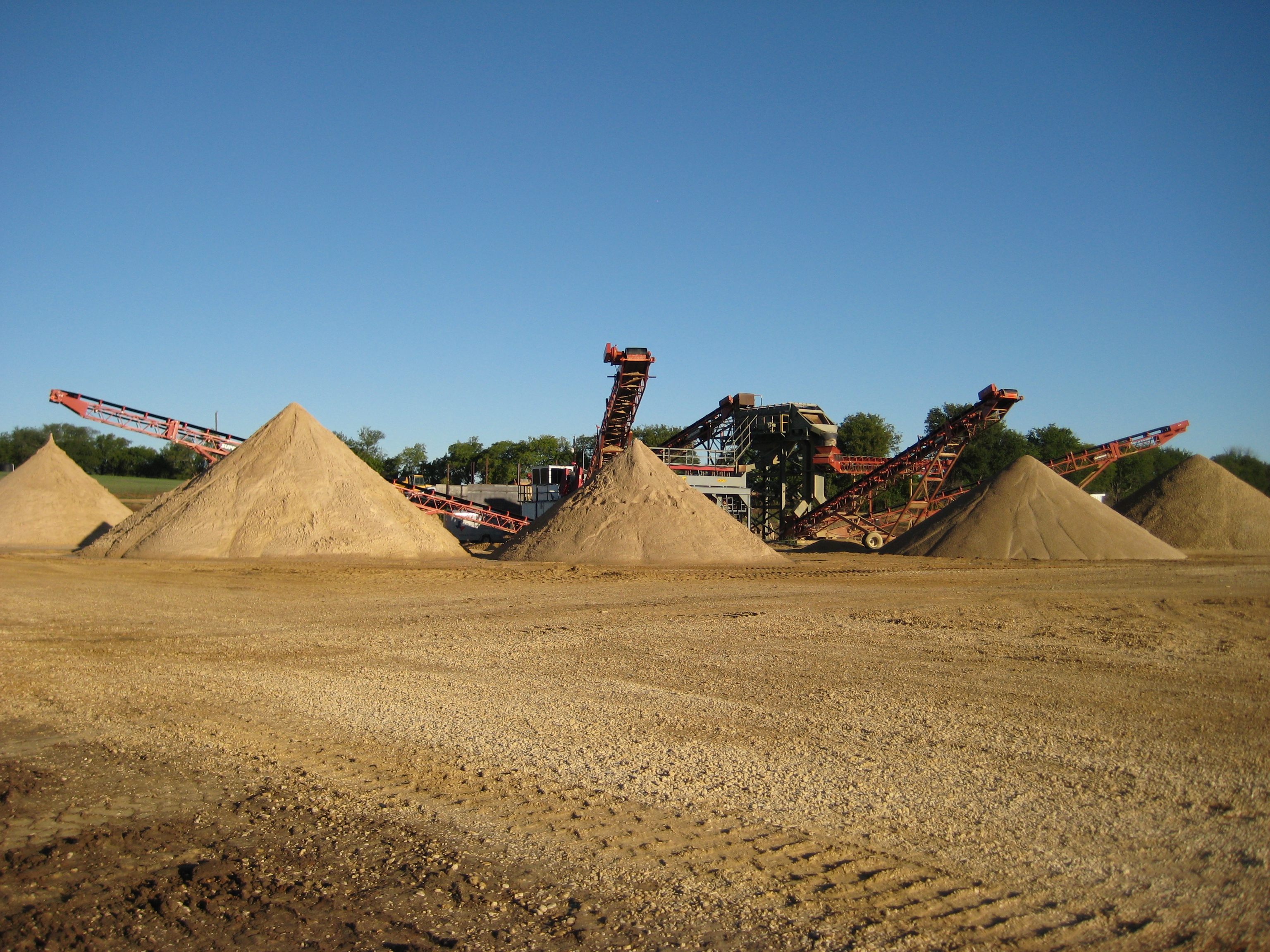 A pile of sand next to some large machines.